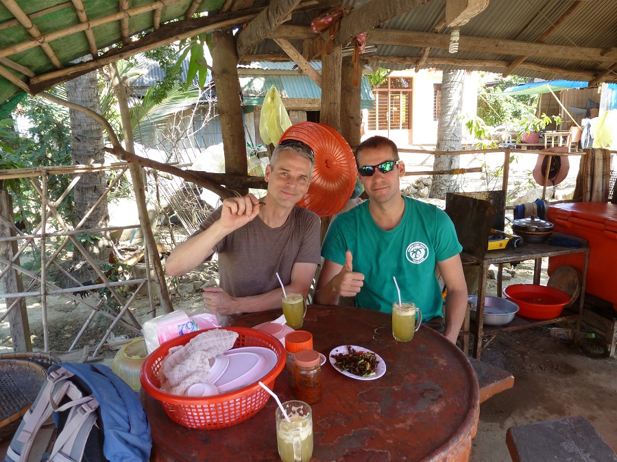 Two men try the crickets for the first time. It the most popular snack in Cambodia.